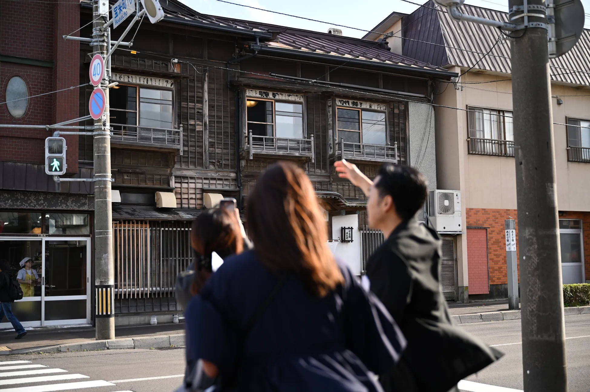 木造の古い建物と、それを見学している人々の様子を捉えた写真